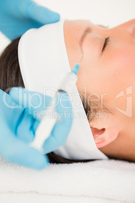 Woman receiving botox injection on her forehead