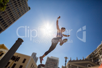 Athletic woman jumping off the bollard