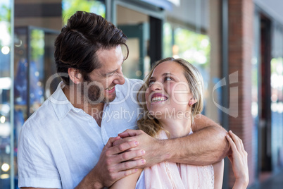 Smiling man putting arm around his girlfriend