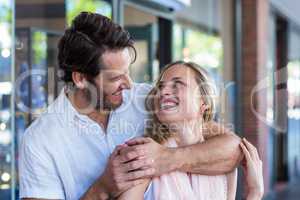 Smiling man putting arm around his girlfriend