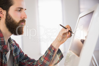 Hipster businessman pointing at computer with pen