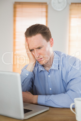 Stressed businessman looking at his laptop