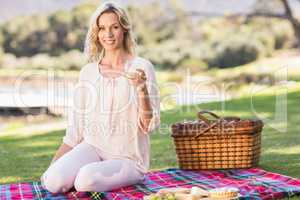 Smiling blonde woman sitting on picnic blanket