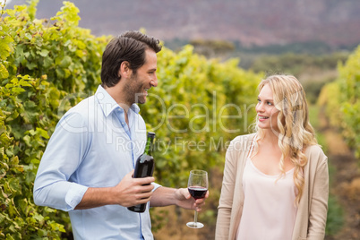 Young happy man offering wine to a young woman