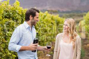 Young happy man offering wine to a young woman