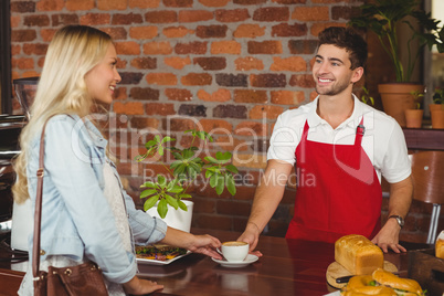 Smiling barista serving a client