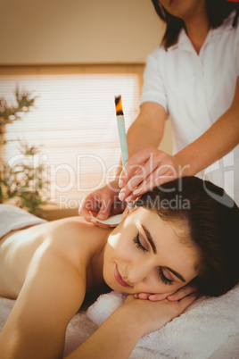 Young woman getting ear candling treatment