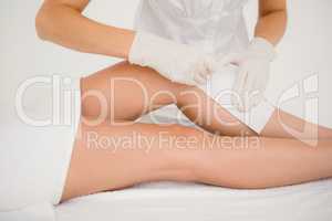 Therapist waxing womans leg at spa center