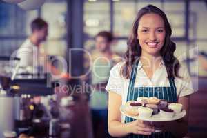 Pretty waitress showing a plate of cupcakes