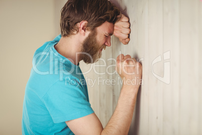 Troubled hipster leaning against wall