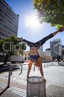 Athletic woman performing handstand and doing split on bin