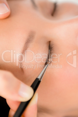 Woman placing fake eyelash on a patient