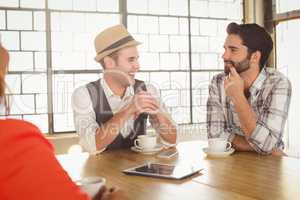 Smiling friends talking and having coffee together