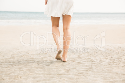 Stylish woman walking on the sand