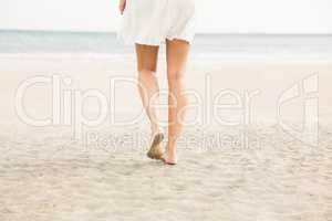 Stylish woman walking on the sand