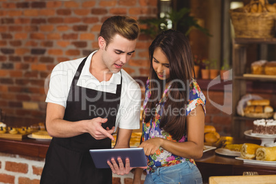 Waiter and pretty customer pointing on tablet computer