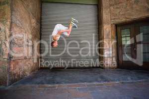 Extreme athlete doing a front flip in front of a building