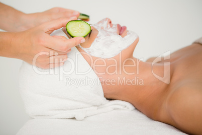 Woman placing cucumber on patient eye