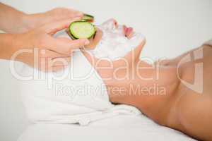 Woman placing cucumber on patient eye