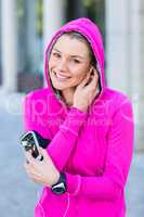 Portrait of a woman wearing a pink jacket putting her headphones