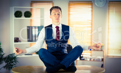 Calm businessman meditating in lotus pose