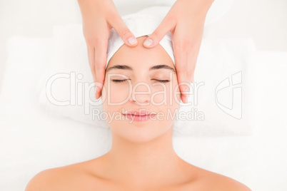 Attractive young woman receiving facial massage at spa center