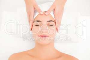 Attractive young woman receiving facial massage at spa center