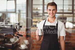 Smiling barista holding jug with milk