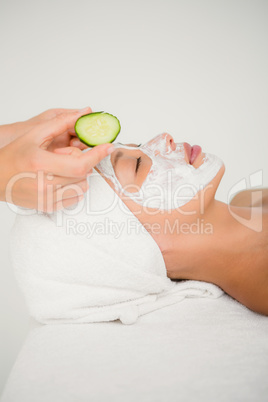 Woman placing cucumber on patient eye