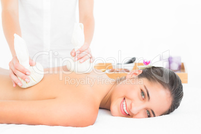 Beautiful brunette enjoying a herbal compress massage