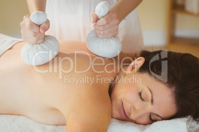 Young woman getting herbal compress massage