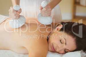 Young woman getting herbal compress massage