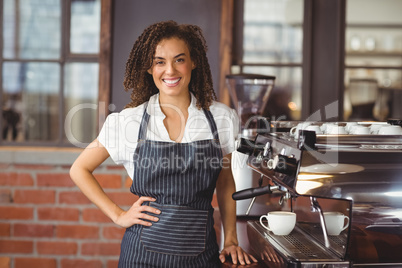 Pretty barista smiling next to coffee machine