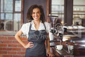 Pretty barista smiling next to coffee machine