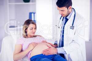Doctor checking stomach of pregnant patient