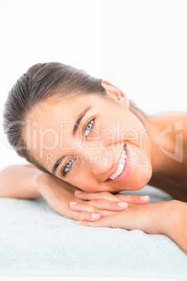 Beautiful brunette lying on massage table smiling at camera