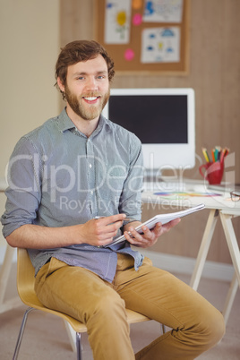 Bearded hipster smiling at camera holding notes