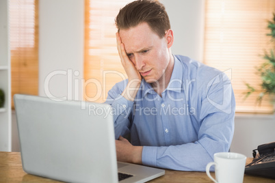 Fearful businessman looking at his laptop