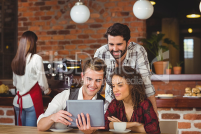 Smiling friends looking at digital tablet