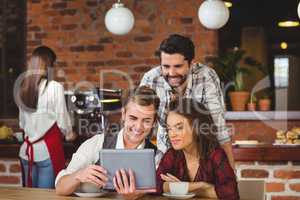 Smiling friends looking at digital tablet