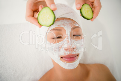 Woman placing cucumber on patient eye