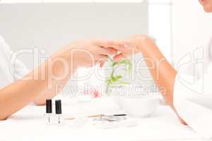 Beautician filing female clients nails at spa beauty salon
