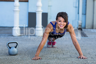 Portrait of smiling athletic woman doing push-ups