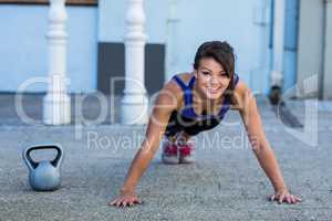 Portrait of smiling athletic woman doing push-ups