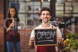 Smiling waiter posing with a chalkboard open sign