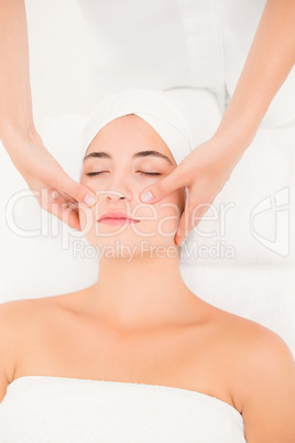 Attractive young woman receiving facial massage at spa center