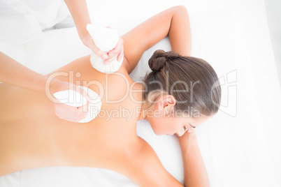 Beautiful brunette enjoying a herbal compress massage