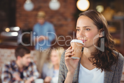 Smiling young woman drinking from take-away cup