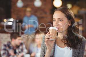 Smiling young woman drinking from take-away cup