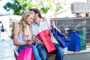 Smiling man with shopping bags kissing his girlfriend